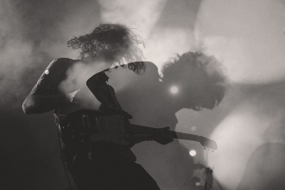 Motion graphic image of a male guitarist on stage surrounded by lights and smoke