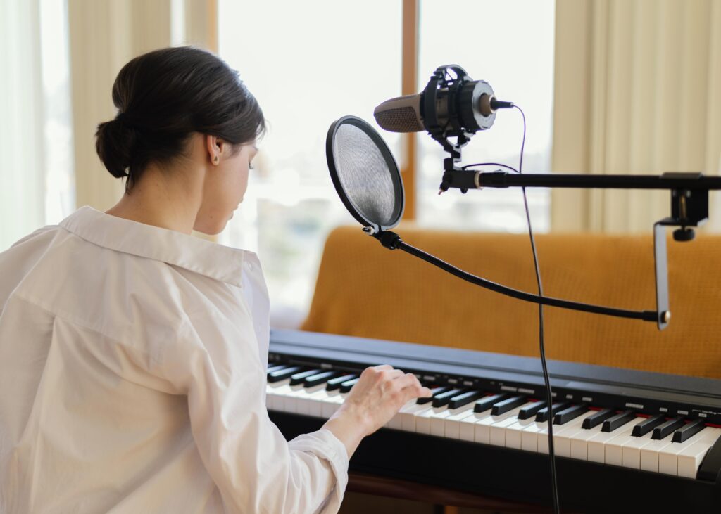 woman composing music on a keyboard with a microphone next to her
