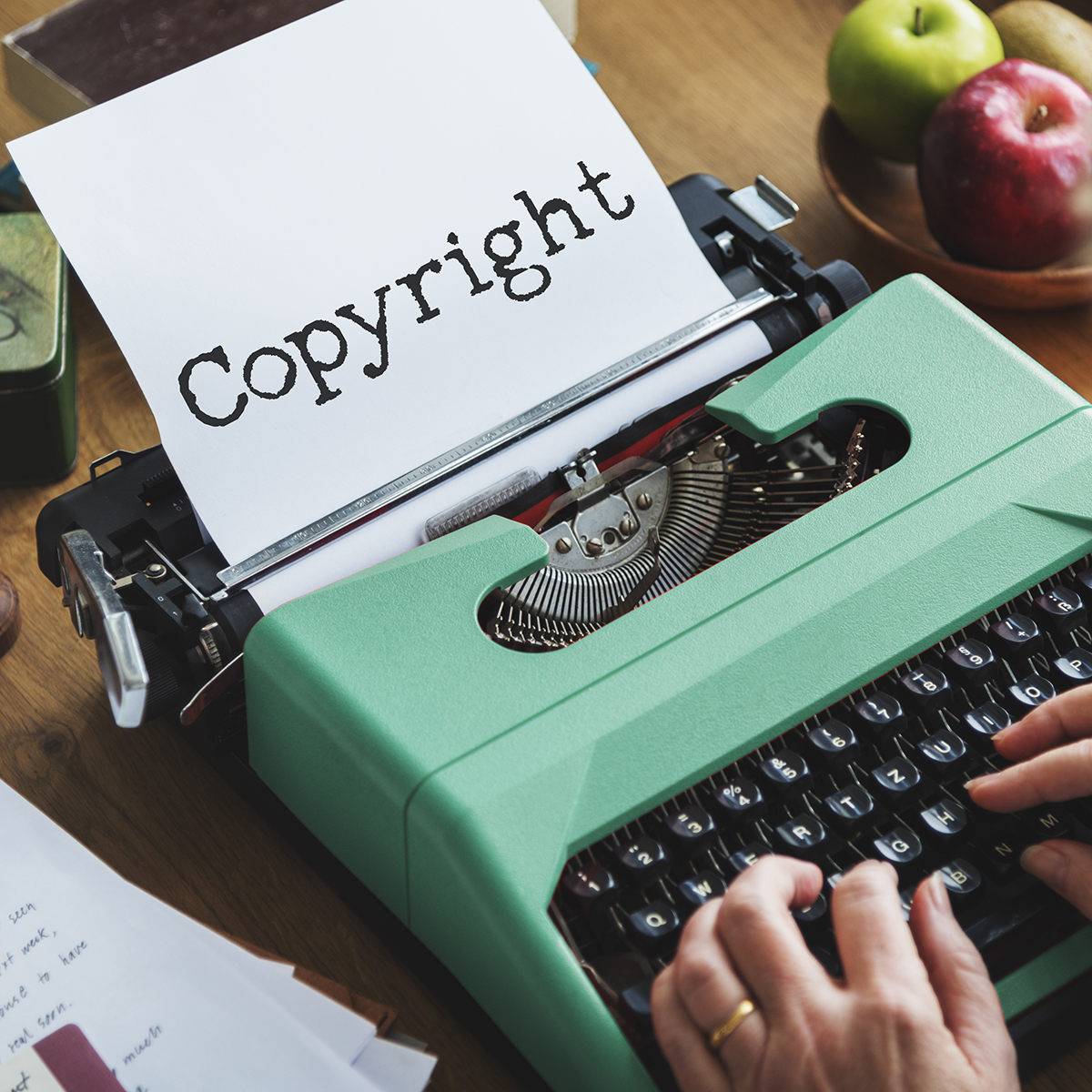 person using an old green typewriter to make the word Copyright